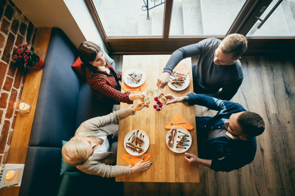 Four friends toasting in a restaurant. Top view.